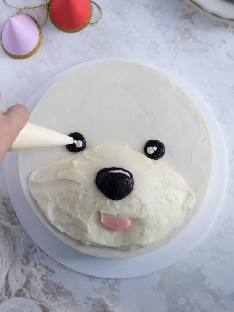 image of eyes and nose being piped onto a westie cake with buttercream