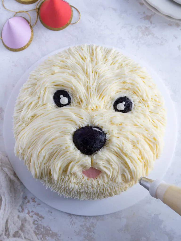 image of white buttercream fur being piped on to a cute westie dog cake