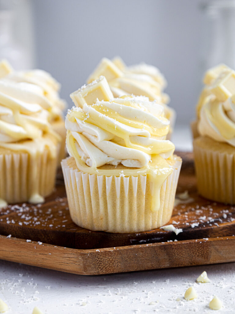 image of white chocolate cupcakes that have been decorated with white chocolate buttercream and drizzled with white chocolate ganache