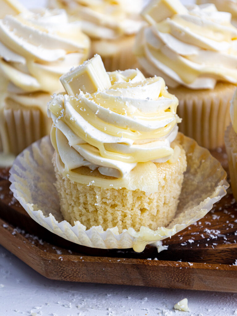 image of white chocolate cupcakes that have been decorated with white chocolate swiss meringue buttercream and drizzled with white chocolate ganache