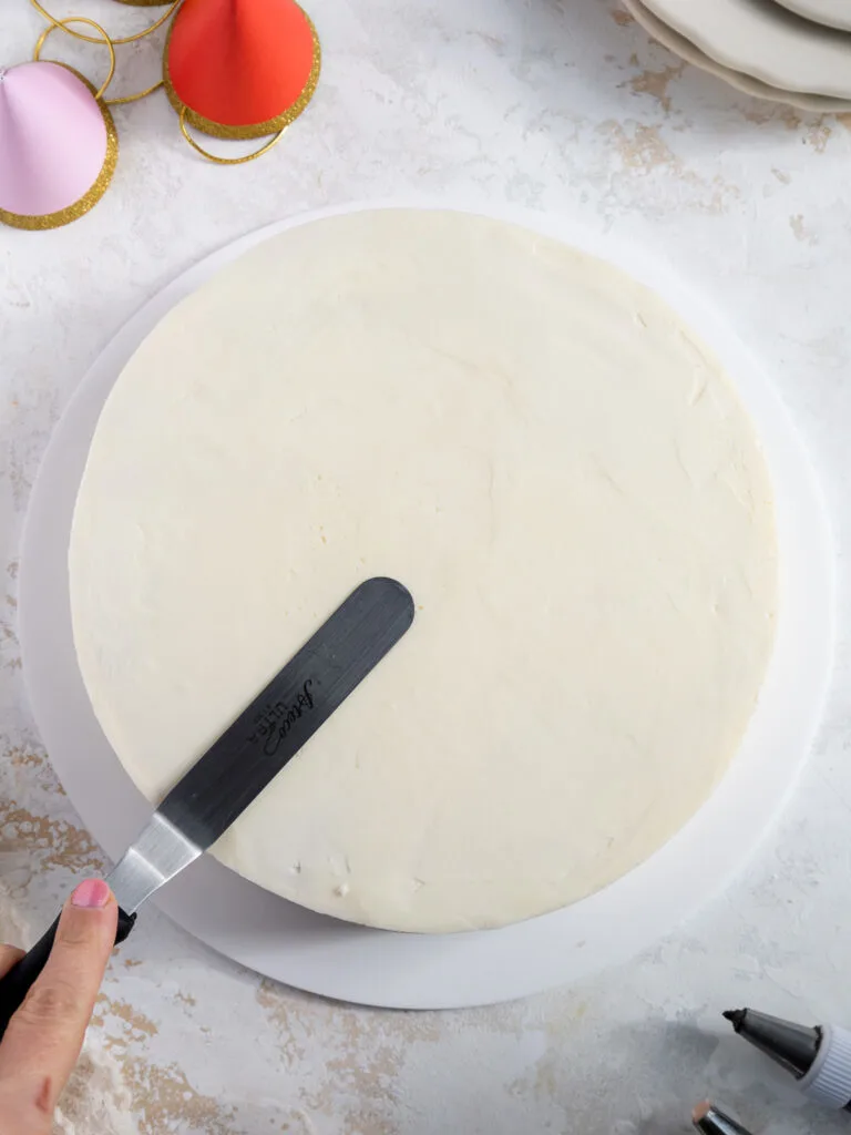 image of vanilla buttercream being smoothed on top of an 8-inch cake