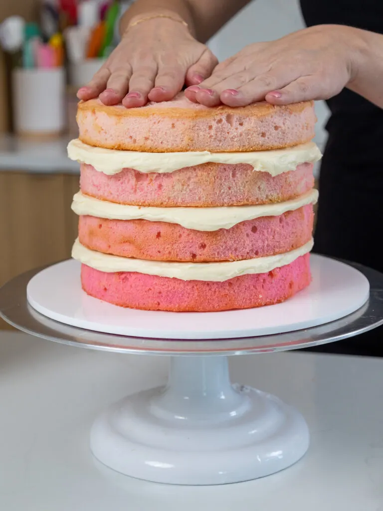 image of pink ombre cake layers that have been filled with buttercream and stacked from the deepest shade to the lightest shade
