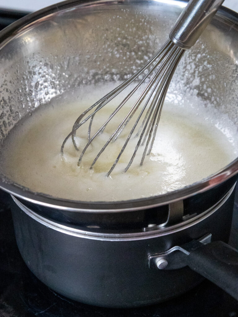 image of egg whites and granulated sugar being heated over a double boiler to make the eggs safe to use in Swiss meringue buttercream