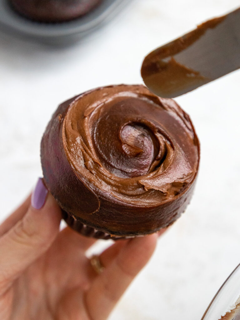 image of chocolate ganache being swirled into chocolate buttercream on top of a death by chocolate cupcake