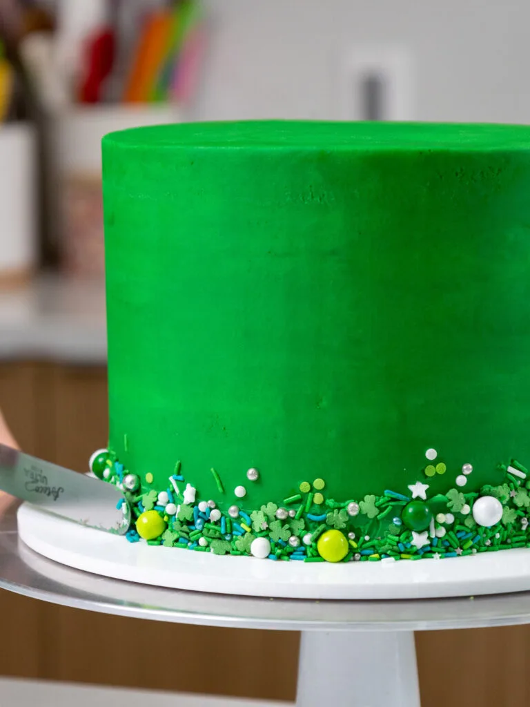 image of sprinkles being added around the base of a green drip cake