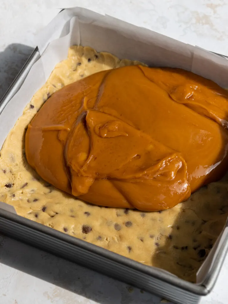image of thick caramel that's been poured on top of a layer of cookie dough to make caramel cookie bars