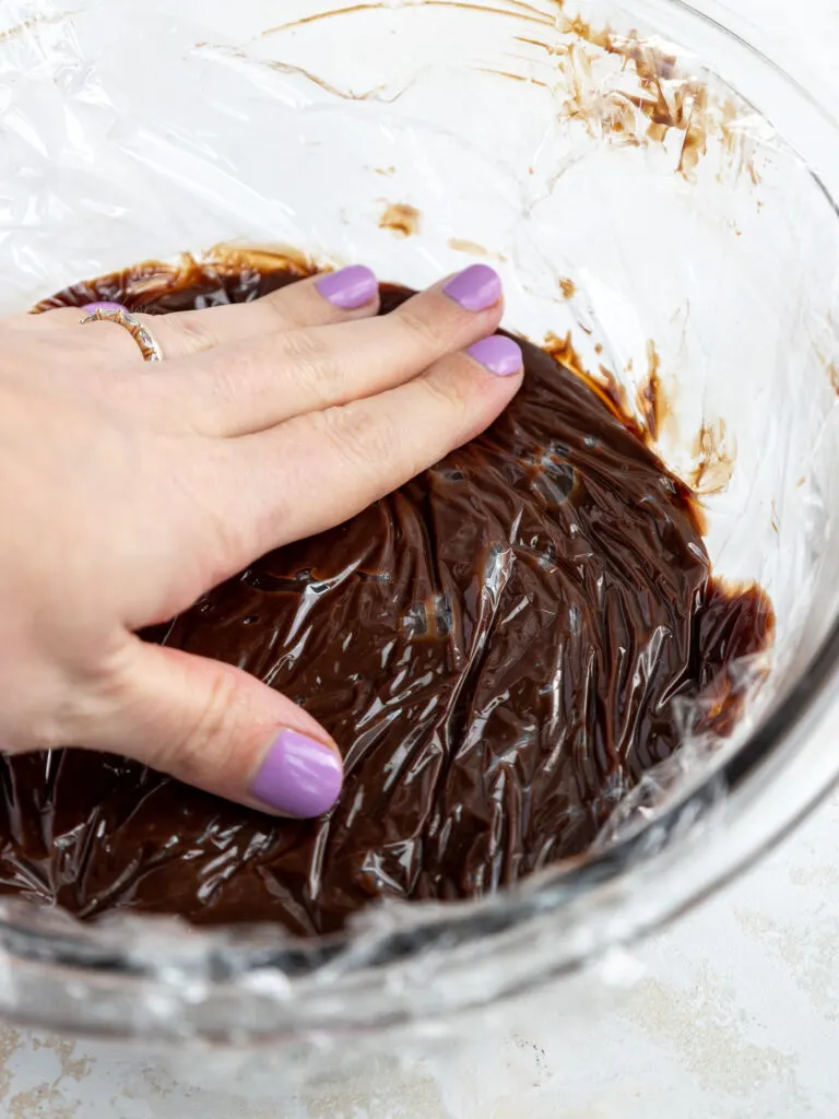 image of spreadable dark chocolate ganache being covered and set aside to cool to room temperature