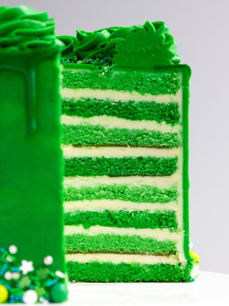 image of a green velvet cake that's been cut into to show it's layers of tender cake and buttercream frosting