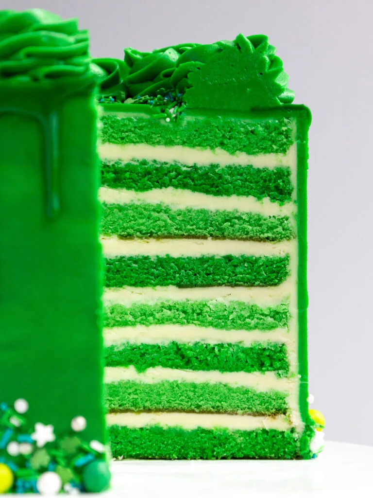 image of a green velvet cake that's been cut into to show it's layers of tender cake and buttercream frosting