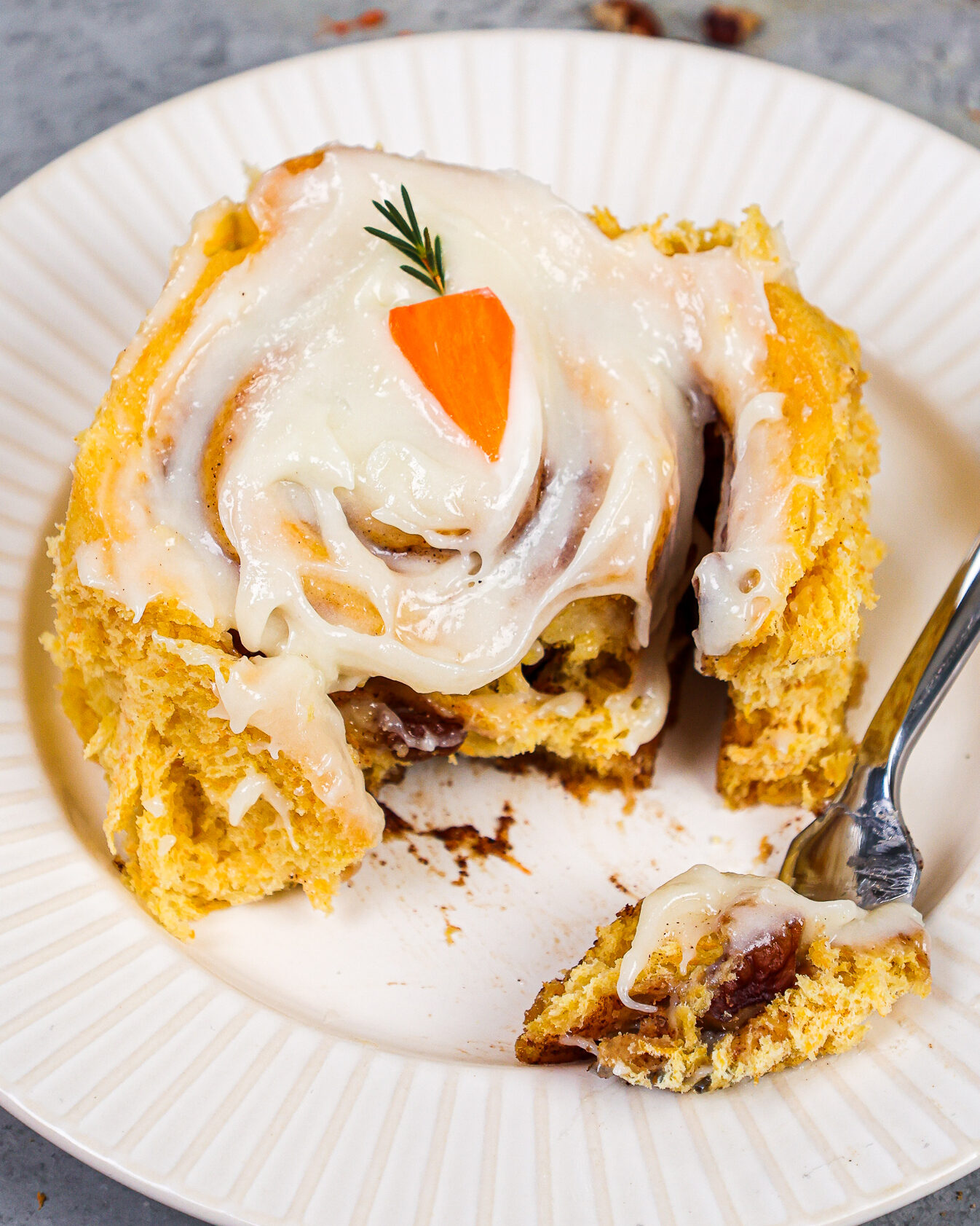 image of a fluffy carrot cake cinnamon roll that's been cut into to show how tender and soft it is