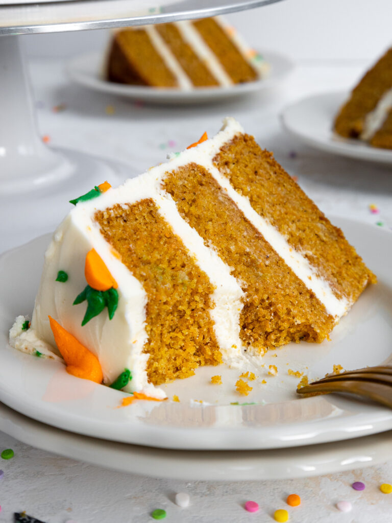 image of a slice of a 6-inch carrot cake on a plate that's been cut into with a fork