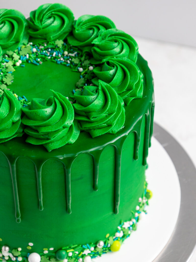 image of a green drip cake from a higher perspective to show it's pretty frosting swirls and green drips on its side