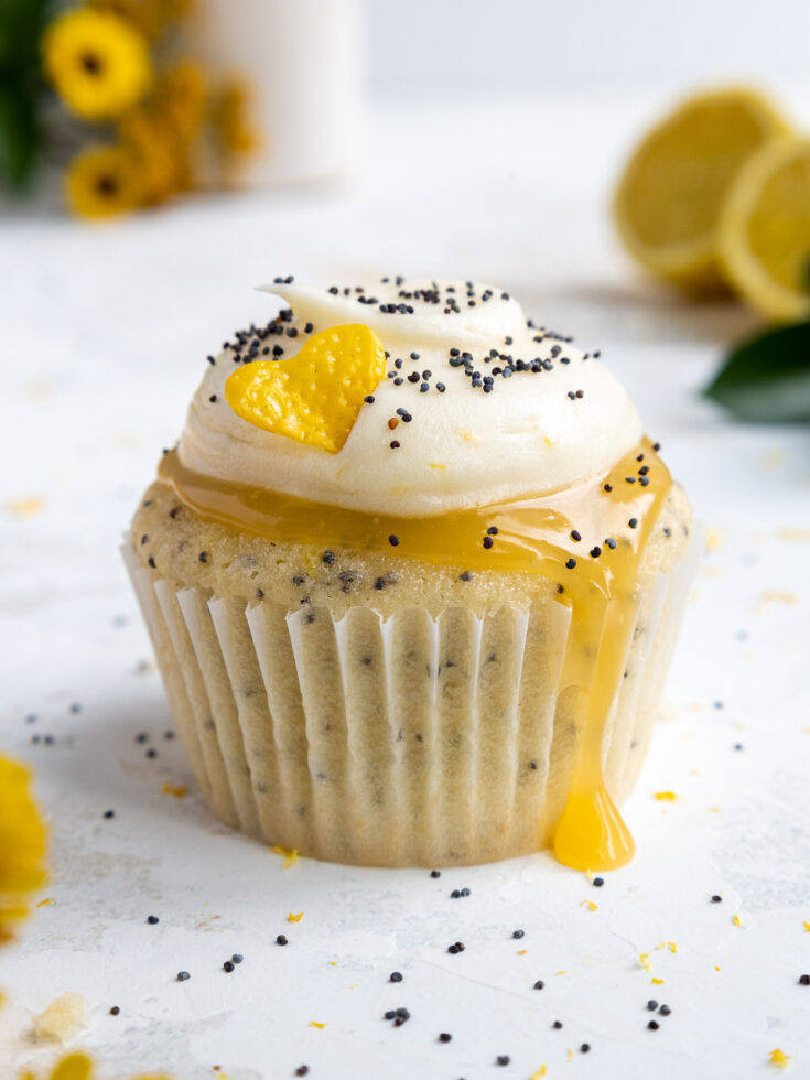 image of a cute lemon poppy seed cupcake that's been frosted with lemon cream cheese frosting and filled with lemon curd