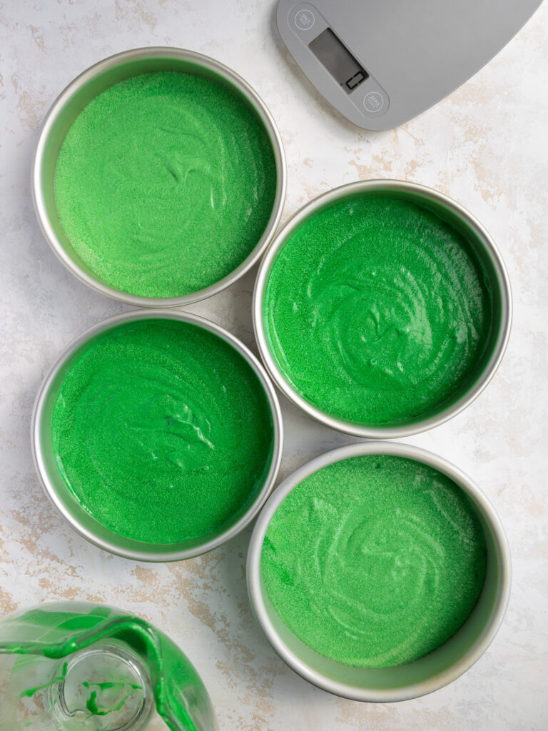 image of green velvet cake batter that has been poured into cake pans and is ready to be baked