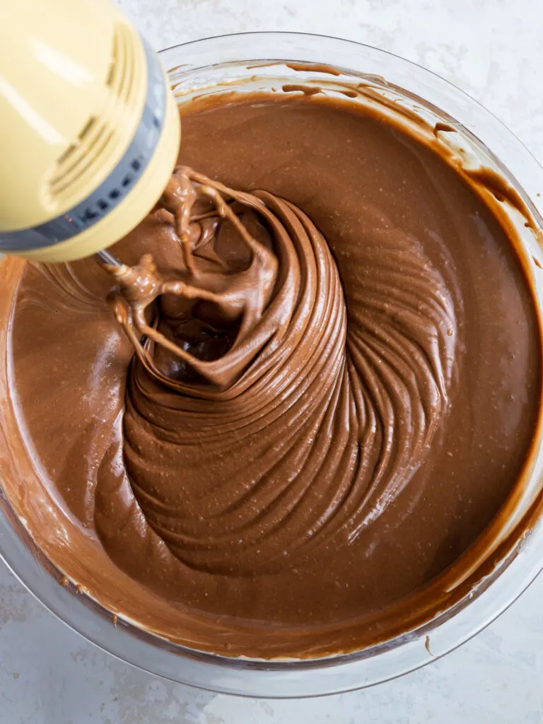 image of chocolate cheesecake batter being mixed with a hand mixer