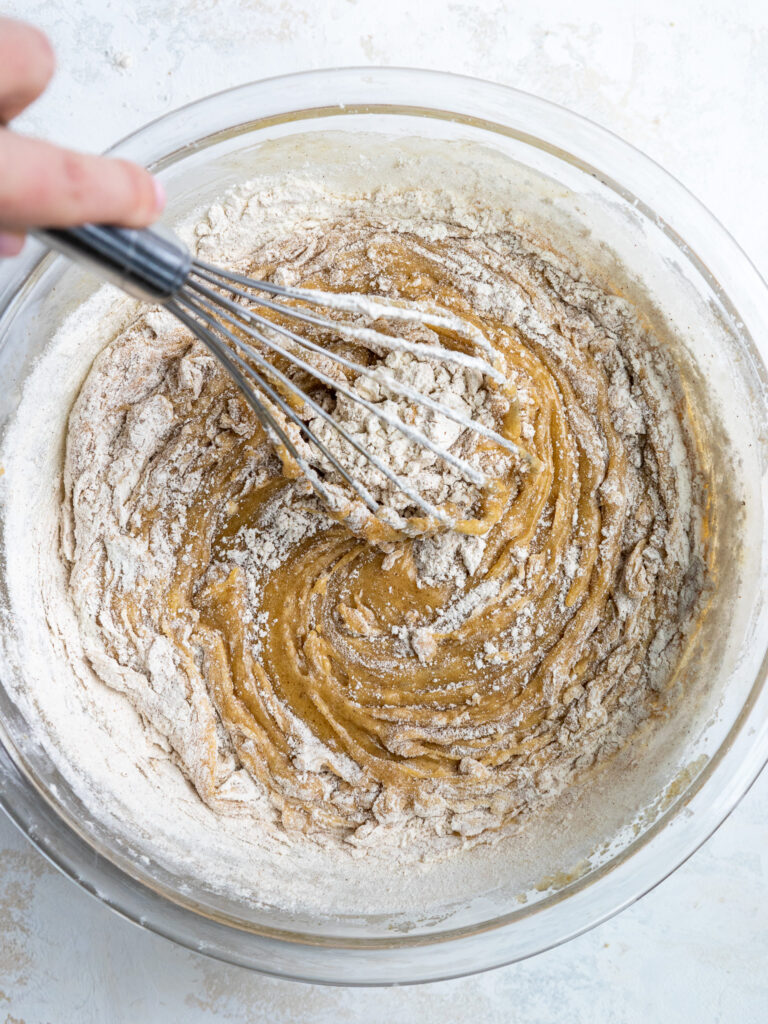 image of dry ingredients being whisked into the wet ingredients to make carrot cake