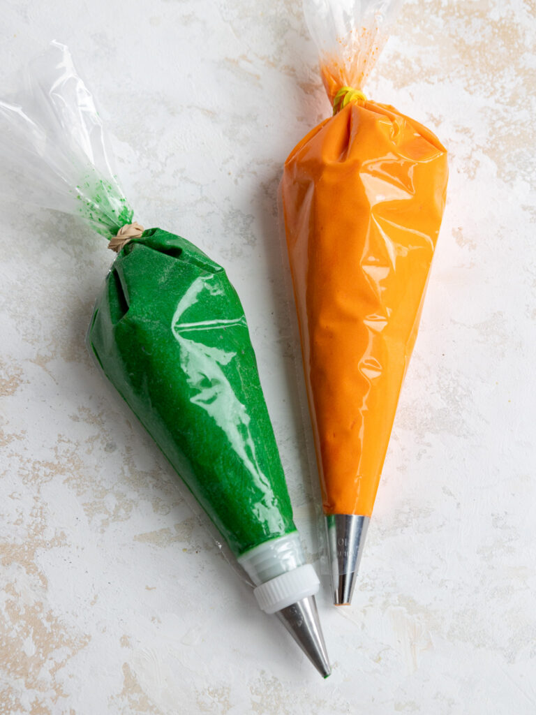 image of orange and green frosting in small piping bags