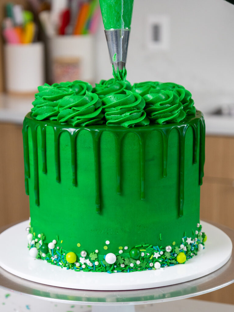 image of green buttercream swirls being piped on top of a bright green drip cake