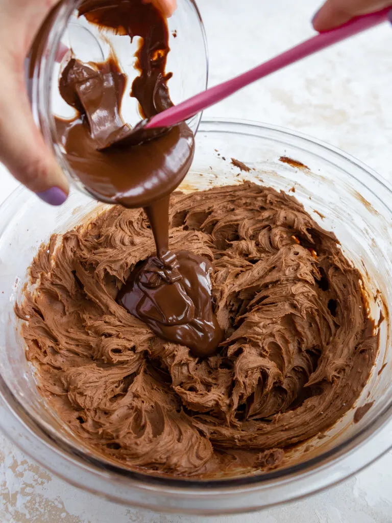 image of melted dark chocolate being added into chocolate buttercream