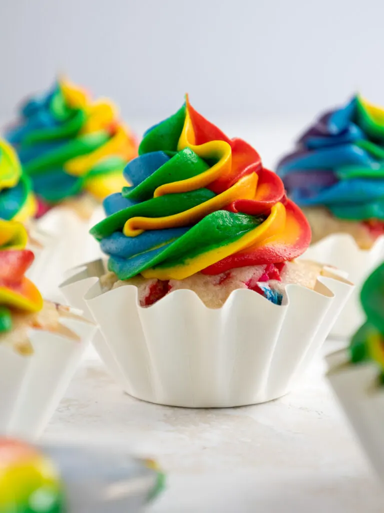 image of a rainbow frosting cupcake surrounded by other cupcakes