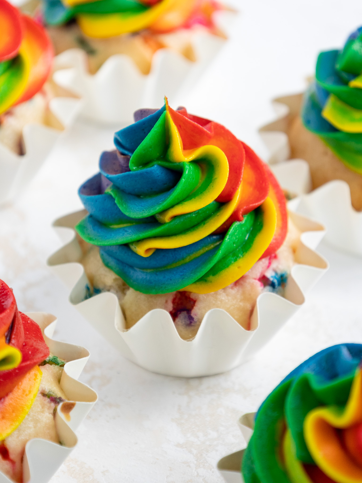 image of a rainbow frosting cupcake surrounded by other cupcakes