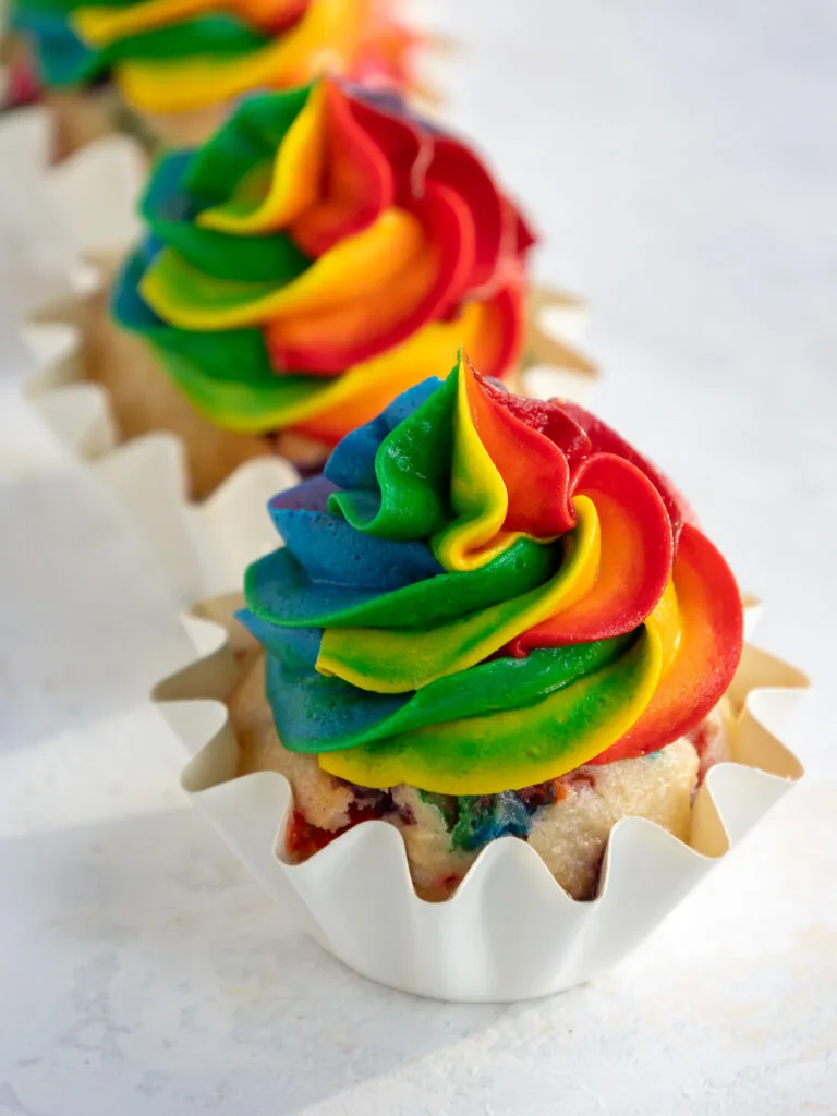 image of cupcakes frosted with rainbow buttercream surrounded by other cupcakes