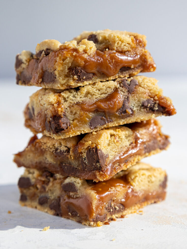 image of caramel cookie bars that have been stacked on top of each other to show their caramel layer