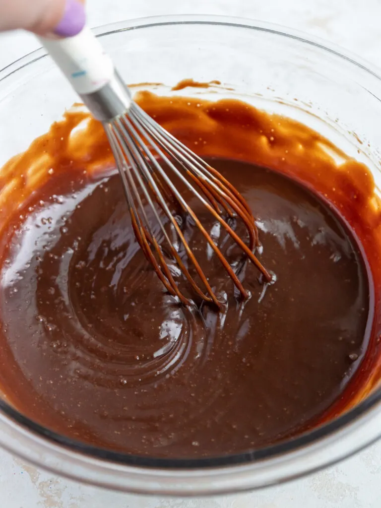 image of chocolate ganache being mixed together in a glass bowl with a whisk