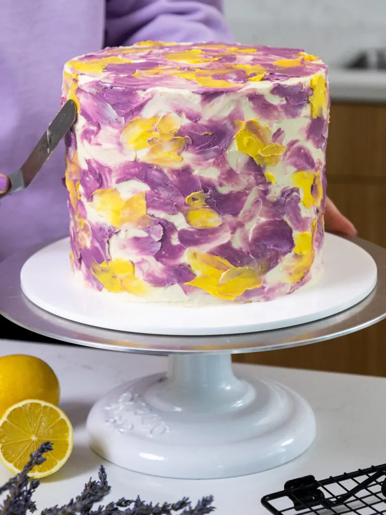 image of a lemon lavender cake that's been placed on a white cake stand
