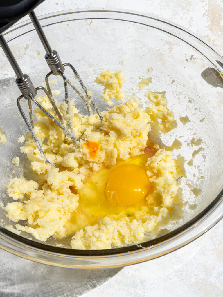 image of an egg and yellow gel food coloring being added into lemon cookie dough