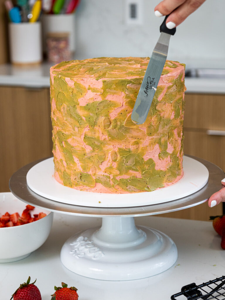 image of a strawberry matcha cake being decorate with green and pink buttercream frosting