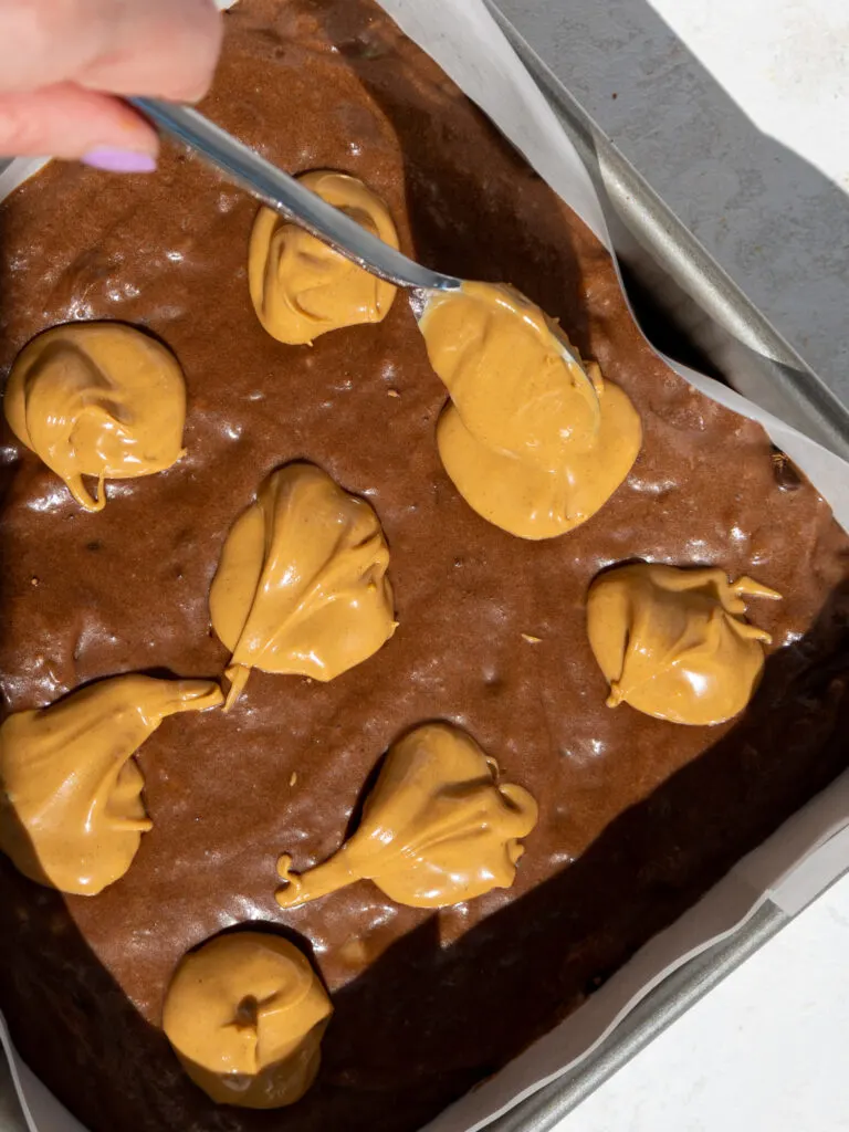 image of warm peanut butter being spooned on top of banana brownie batter