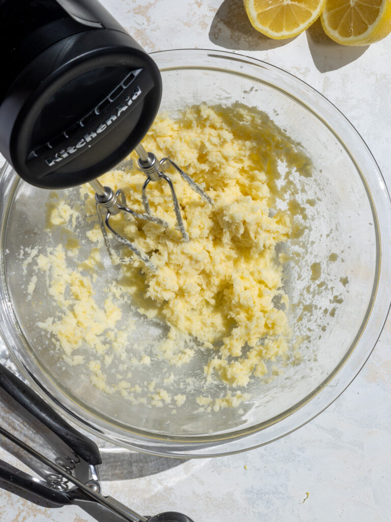image of butter being creamed with lemon sugar using a hand mixer