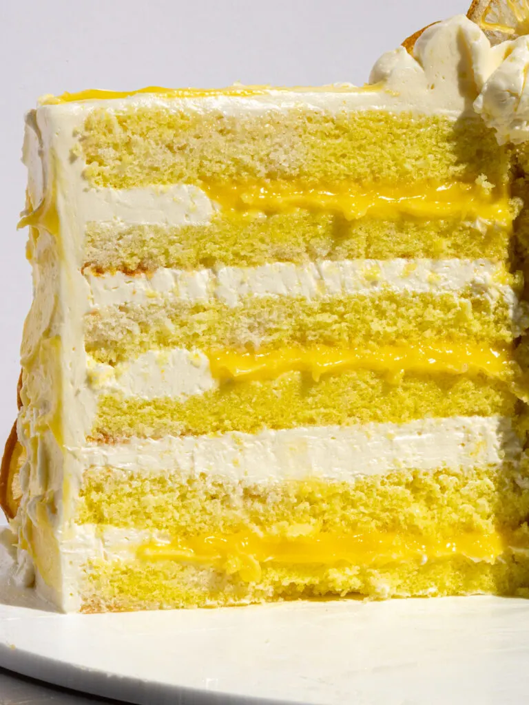 image of a lemon curd cake that's been cut into to show its lemon curd filling and lemon Swiss meringue buttercream