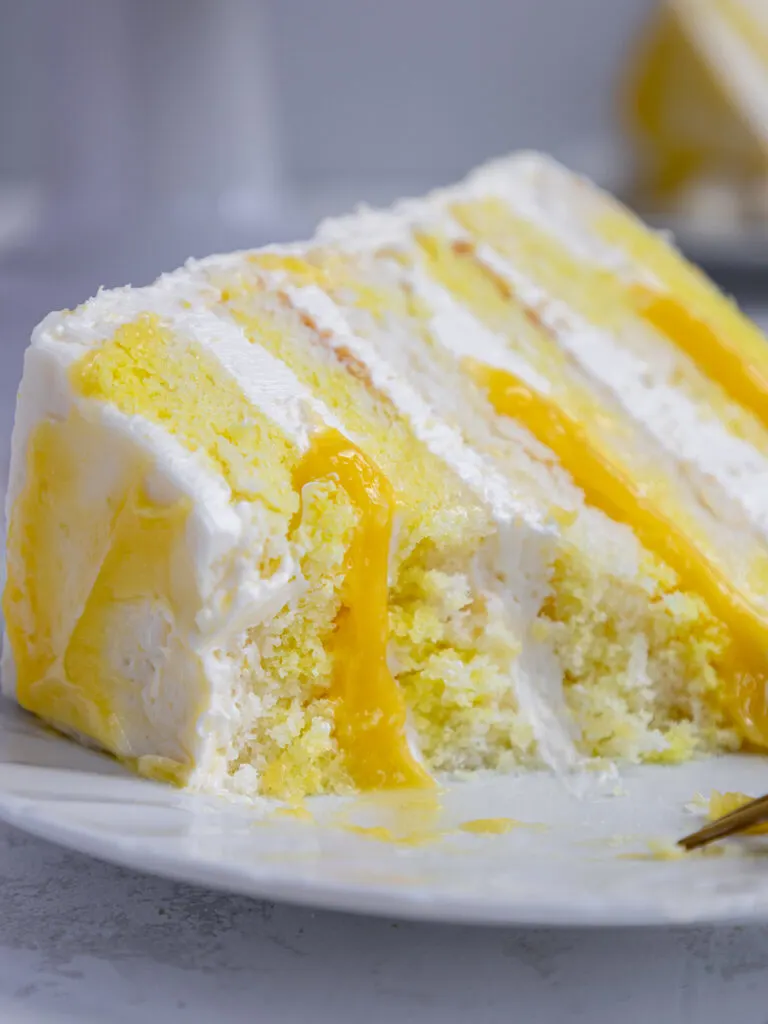 image of a slice of lemon curd cake on a plate that's been cut into to show its filling