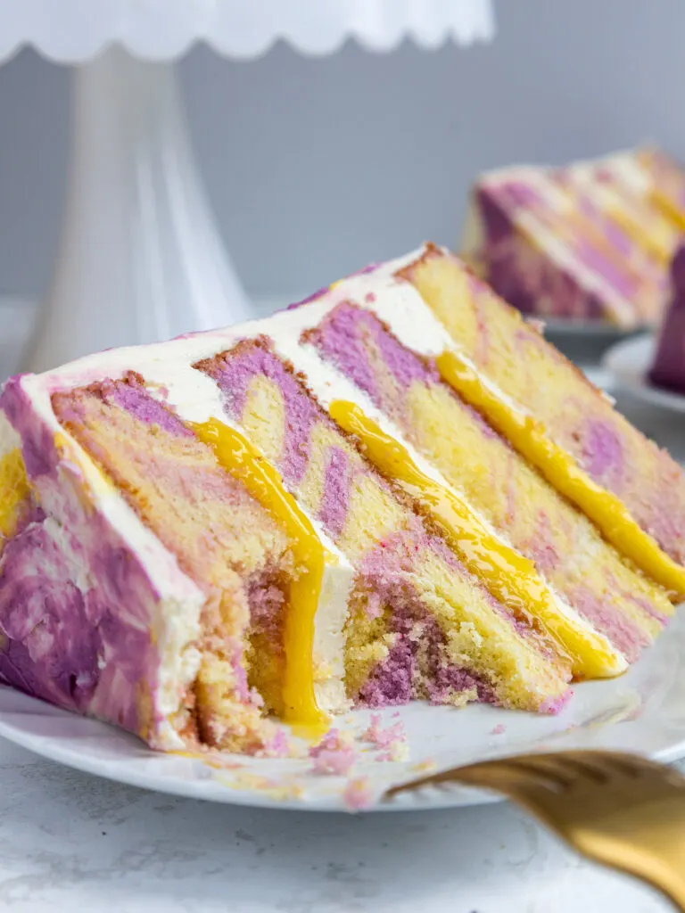 image of a slice of lemon lavender cake that's been cut into to show its lemon curd and lavender buttercream filling
