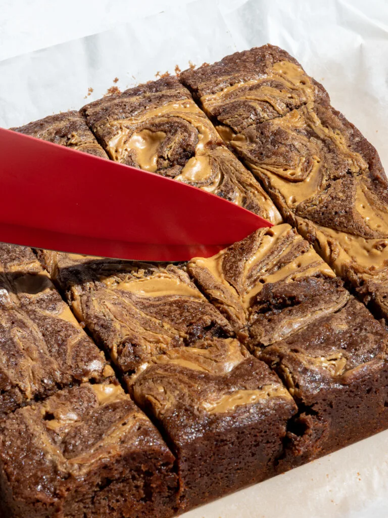 image of peanut butter banana brownies being cut into with a red knife