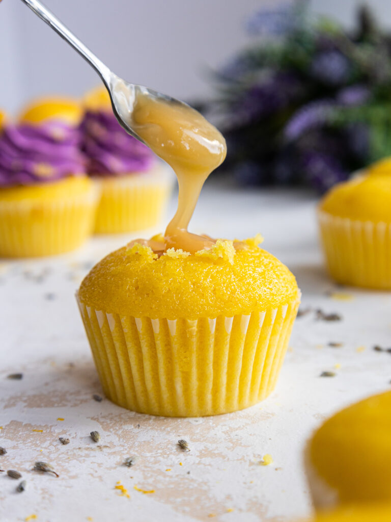 image of a yellow lemon cupcake being filled with lemon curd
