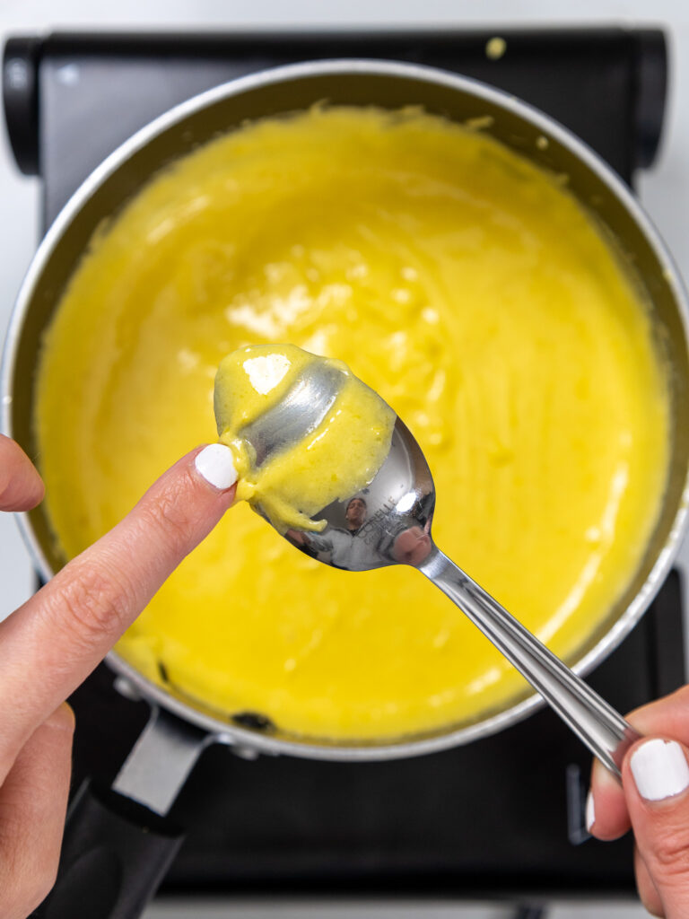 image of lemon curd that's been cooked and has thickened to the point of keeping its shape on the back of a spoon