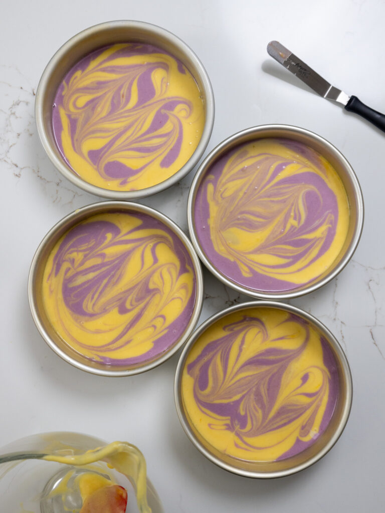 image of lavender lemon cake batter that's been swirled together in cake pans and is ready to be baked