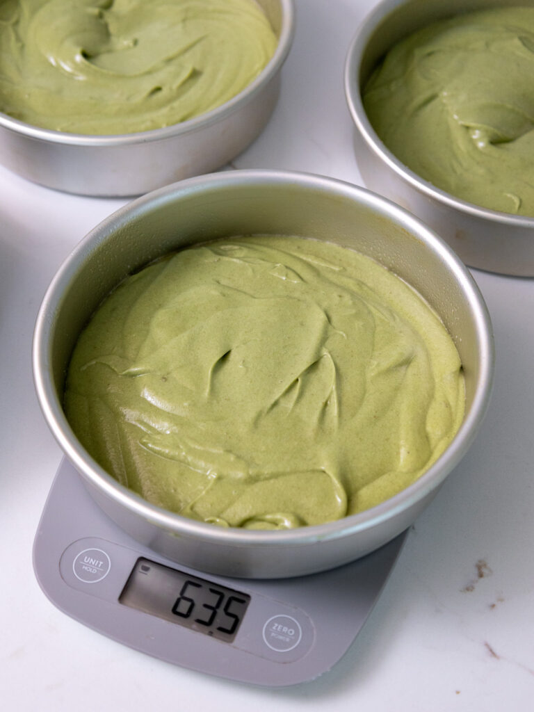 image of matcha cake batter being weighted in pans on a scale