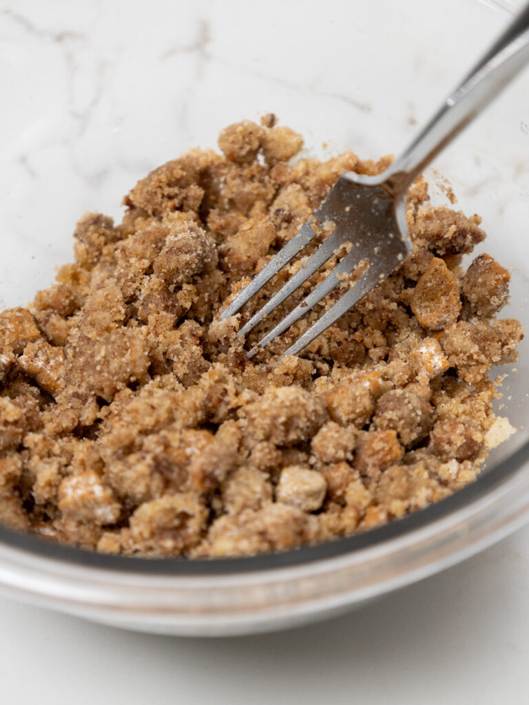 image of biscoff streusel being mixed together with a fork in a glass mixing bowl