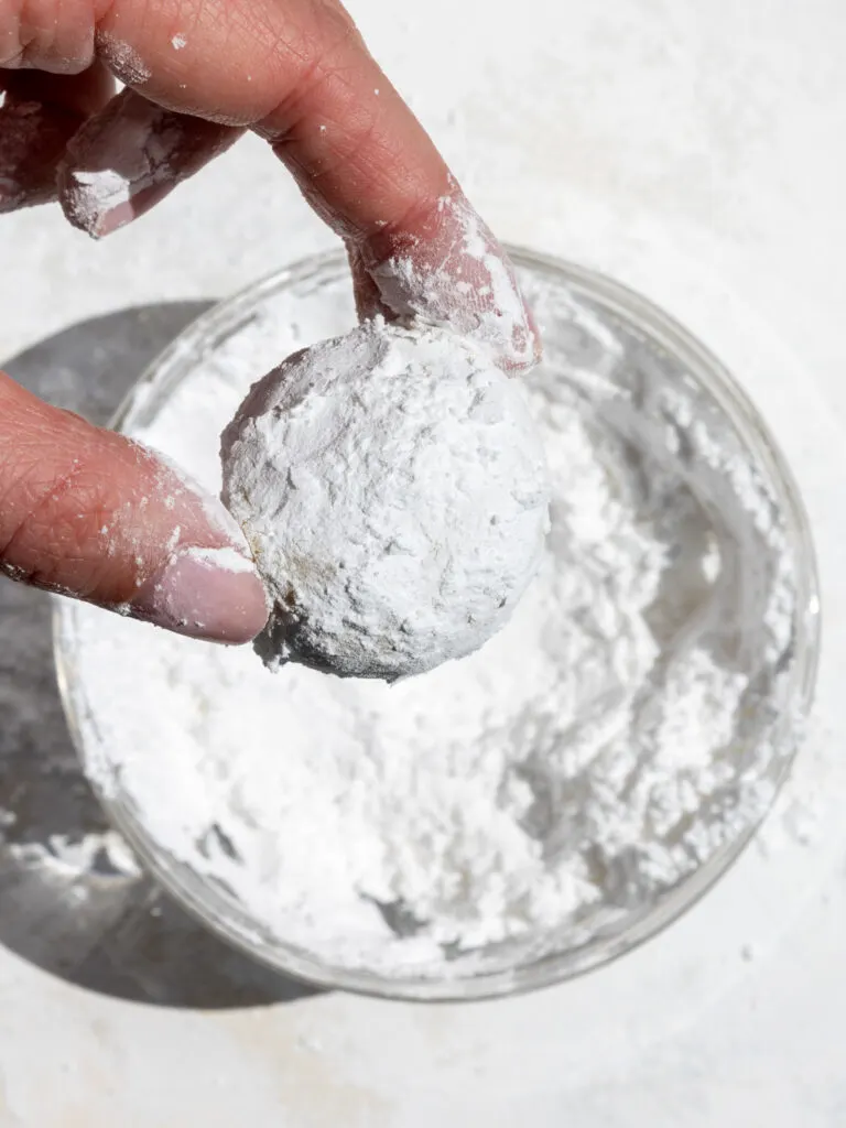image of lemon crinkle cookie dough being coated in powdered sugar