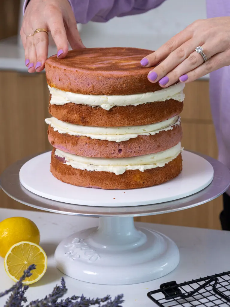 image of lavender lemon cake layers being filled and stacked