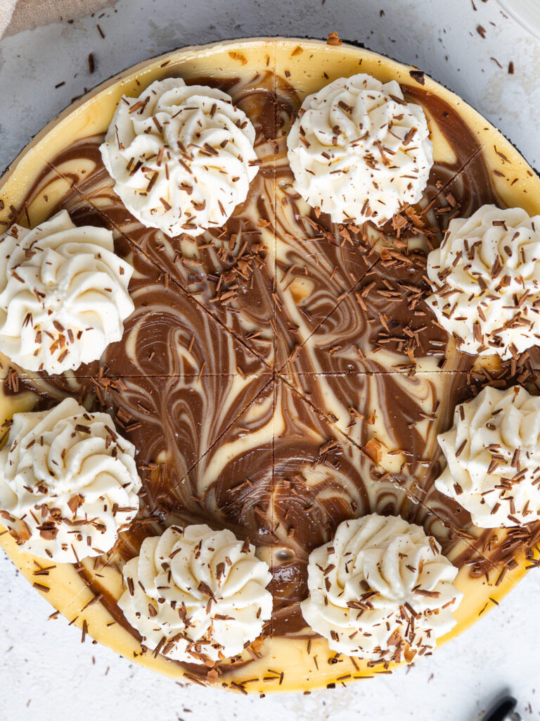 image of a marbled cheesecake that's been decorated with whipped cream and chocolate shavings