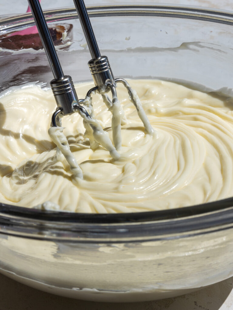 image cream cheese and sugar being mixed together with a hand mixer