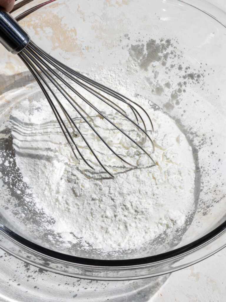 image of granulated sugar and cornstarch being whisked together in a glass bowl