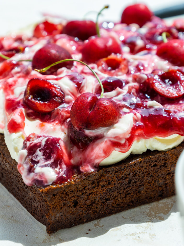 image of black forest brownies that have been topped with homemade whipped cream and a thick cherry topping
