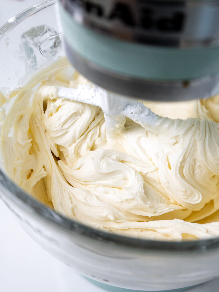 image of vanilla buttercream frosting being mixed in a stand mixer with a paddle attachment