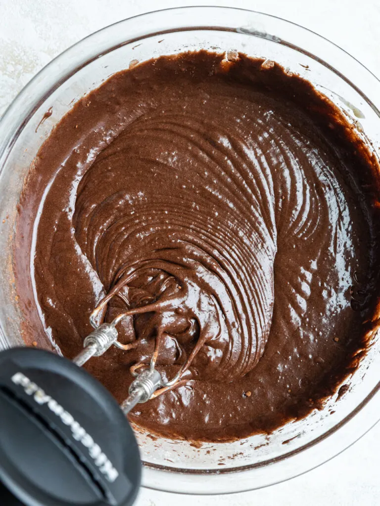 image of dark chocolate brownie batter being mixed together with a hand mixer
